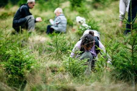Happy family collecting wild berries in forest. Active vacation. Travel background