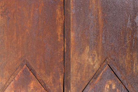 Worn rusty metal texture background. Old iron sheet, door or fence, backdrop. Wall of tank with angular patterns. Template for designers and illustratorsの写真素材