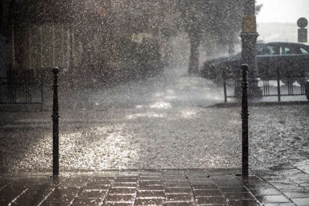 Rain in the city. Road, pavement, car in rain, close up. Water splashes, spills on roadway.の写真素材