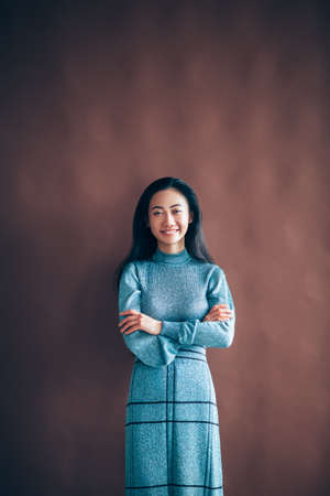 Portrait of happy asian woman with crossed arms posing in studioの写真素材