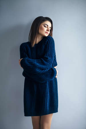 Beautiful dreaming girl in blue dress hugging herself. Happiness conceptの写真素材