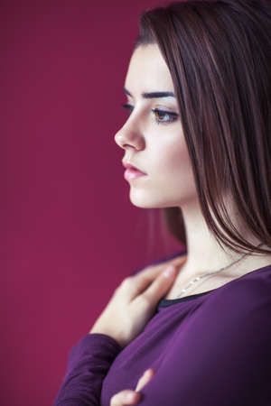 Close up profile portrait of young beautiful woman against pink background