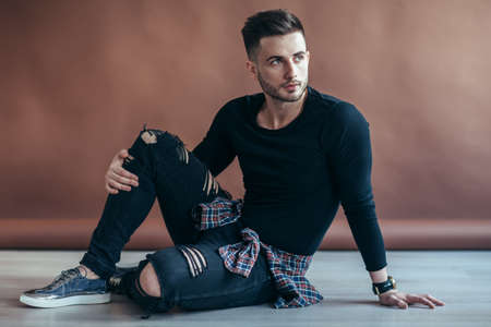 Stylish handsome man posing sitting on floor. Fashion conceptの写真素材