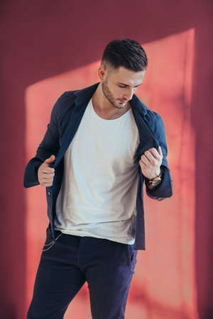 Handsome young man posing in red background in studio. Stylish manの写真素材
