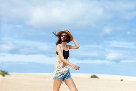 Beautiful boho styled woman posing on the desert. Fashion portrait in motionの写真素材