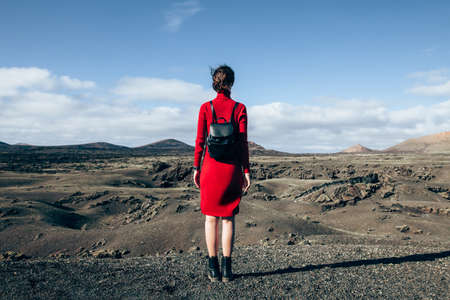 Back view of traveler woman enjoying unique volcanic landscapes of Timanfaya National Park, Lanzarote, Canary island. Travel and vacation conceptの写真素材