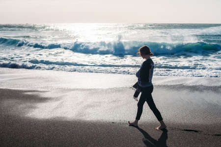 Young woman walking on an empty black sand beach. Travel vacation conceptの写真素材