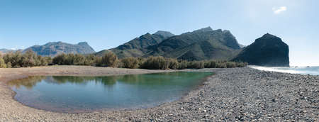 Beautiful panorama of lake in ocean beach with mountains on background in Gran Canaria, Canary islands, Spain.の写真素材