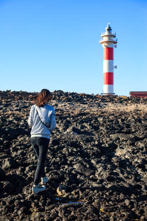 Woman walking on the beach to lighthouse. Travel conceptの写真素材