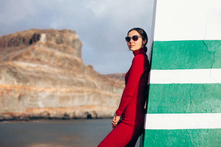 Young beautiful woman posing near lighthouse. Summer travel conceptの写真素材