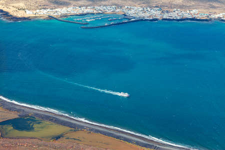 Ocean surface aerial view. Birds eye view drone of Canary island seashore and luxury yacht. Summer...