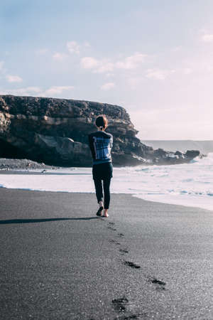 Lonely barefoot woman walking on ocean beach. Relax concept