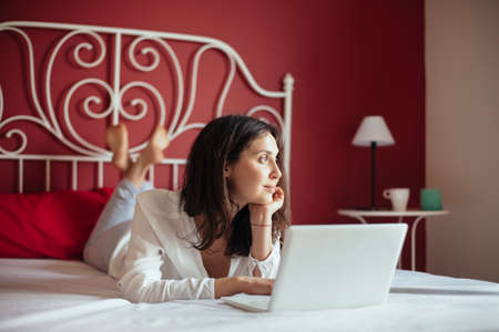 Happy beautiful woman relax on bed working on a laptop in home. freelance concept