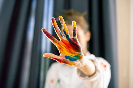 Woman showing stop gesture with hand painted in colorful paintsの写真素材
