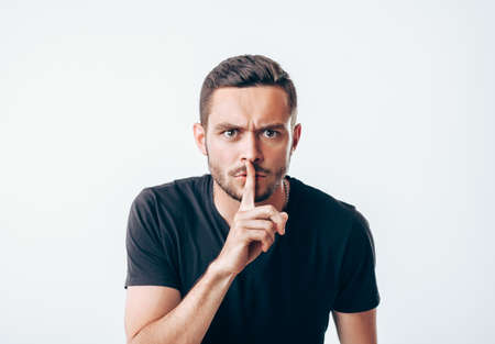 Young man holding index finger on lips asking for silence.  Secret conceptの写真素材