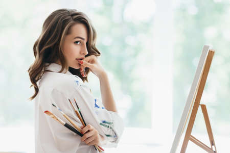 Beautiful woman artist with brushes posing in her studio. Beauty conceptの写真素材