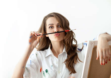 Portrait of young woman making faces and depicts mustache with help of paintbrush. Fun conceptの写真素材