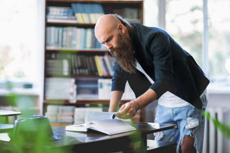 Hipster bearded student studying in library at the universityの写真素材