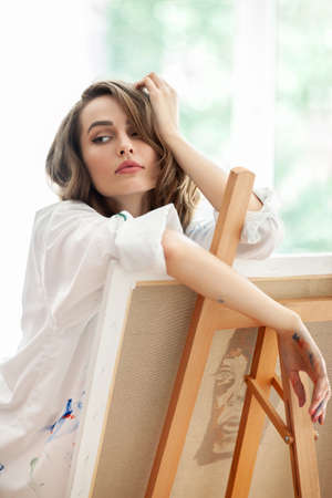 Pretty female artist posing by easel on art studio. Creative conceptの写真素材