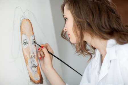 Closeup of artist painting woman portrait in her studioの写真素材