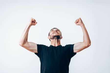 Handsome young man with arms up celebrating successの写真素材