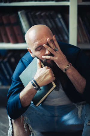 Depressed man with book sitting on floor head in hands. Tragedy conceptの写真素材