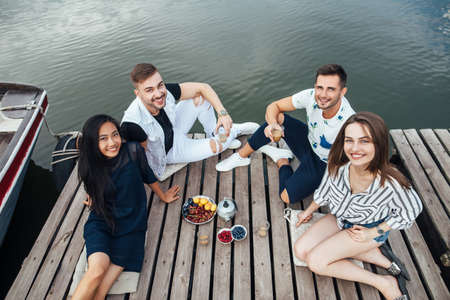 Group of happy young friends relaxing on river wooden pier. Top view. Summer vacation conceptの写真素材