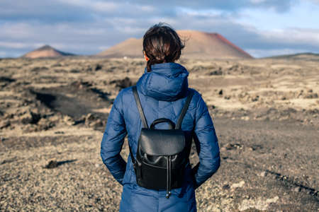 Back view of traveler woman enjoy unique volcanic landscapes of Timanfaya National Park, Lanzarote....