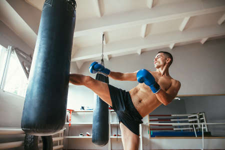 Male boxer workout high kick on the punching bag in gym. Sport conceptの写真素材