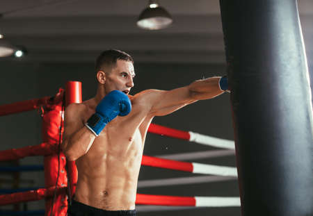 Male boxer hitting punching bag at a boxing studio. Sport training conceptの写真素材