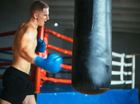 Male boxer hitting punching bag at a boxing studio. Sport training conceptの写真素材