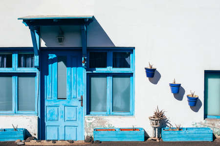 Traditional canarian house with white walls, blue door and window on Lanzarote island