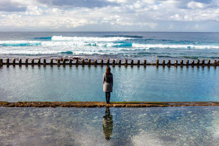Lonely woman looking to the ocean waves. Relax conceptの写真素材
