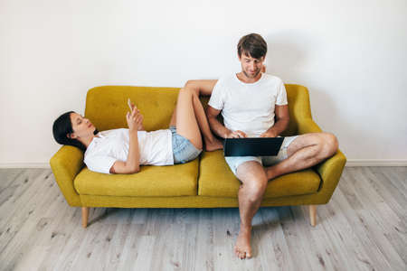 Young couple using gadgets while relaxing together at homeの写真素材
