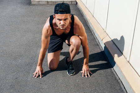Runner in running start pose on the city street. sprinter training outdoorの写真素材