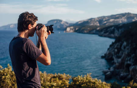 Male photographer taking photo of beautiful Italy coastline and mountainsの写真素材