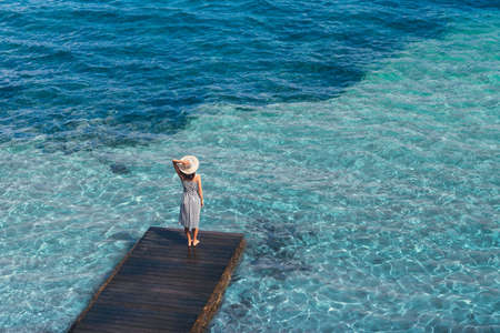Beautiful woman relaxing on pier in Sardinia island, Italy. Summer vacations concept. Top viewの写真素材
