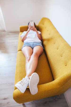 Top view of young woman using smartphone while lying in bed. Relax conceptの写真素材