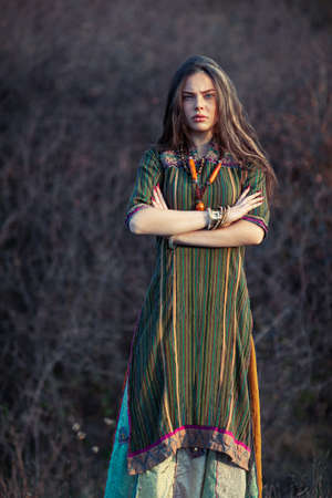 Beautiful hippie woman at sunset outdoors. Crossed arms