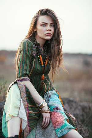 Fashion portrait of young hippie woman at sunset posing on nature backgroundの写真素材