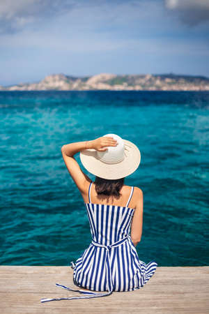 Happy woman in hat relaxing on sea pier in Sardinia island, Italy. Summer vacations conceptの写真素材