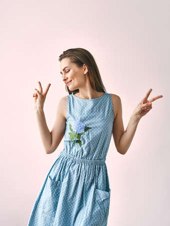 Portrait of young pretty girl showing peace gesture on pink backgroundの写真素材