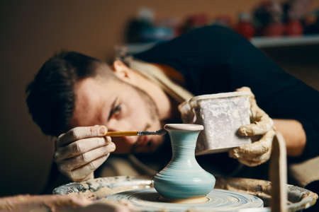Man painting handmade pottery at ceramic workshop. Art conceptの写真素材