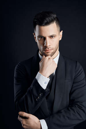 Handsome thoughtful man in black suit on dark background. Man beautyの写真素材