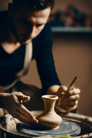 Man potter working on potters wheel making ceramic pot from clay in pottery workshop. art conceptの写真素材