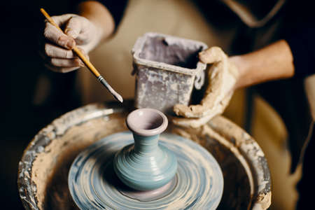 Man painting handmade pottery at ceramic workshop. Art conceptの写真素材