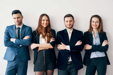 Young smiling business people with arms crossed lean to wall in officeの写真素材