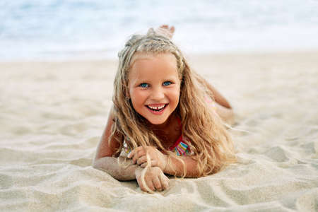 Adorable little blonde girl relax on sandy beach enjoy seaの写真素材