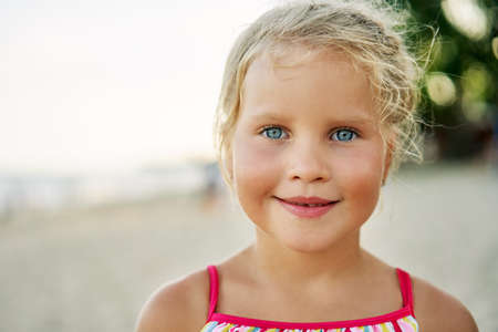 Close up portrait of happy cute little girl. Smiling blonde child on summer