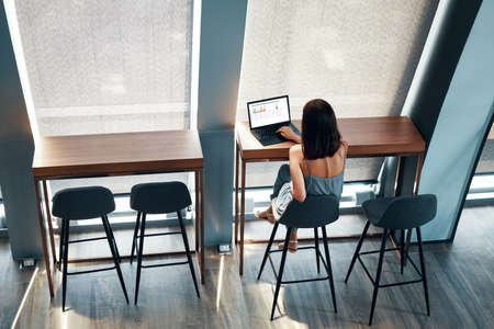 Top view of young beautiful woman working on laptop in modern office spaceの写真素材